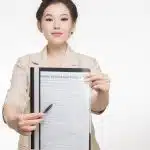 Woman in Corporate Attire Holding A Home Insurance Policy