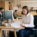 Femme concentrée travaillant à son bureau dans un open space moderne et bien organisé, illustrant la productivité en entreprise