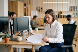 Femme concentrée travaillant à son bureau dans un open space moderne et bien organisé, illustrant la productivité en entreprise